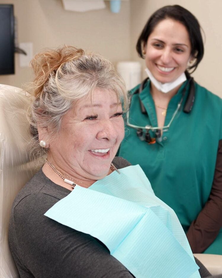 Dr. Sheoran celebrating with a happy patient after dental implant smile restoration