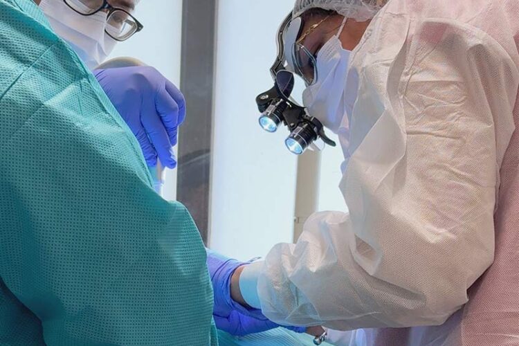 Dr. Sheoran wearing magnification loupes and protective equipment during an implant procedure