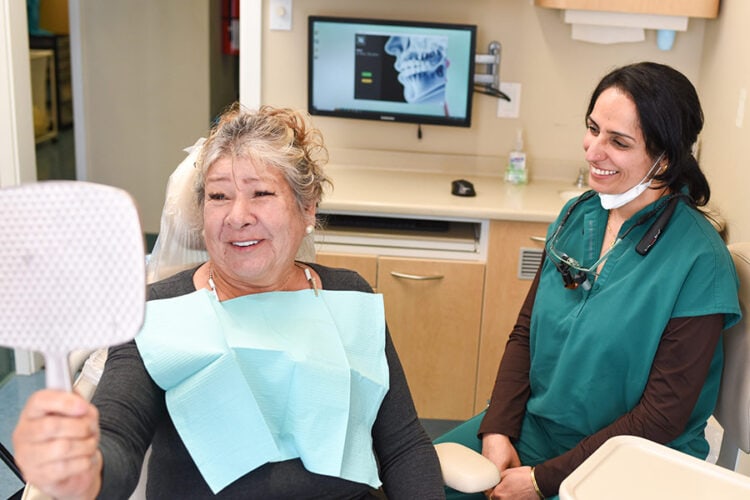 Dr. Sheoran celebrating with a happy patient after dental implant smile restoration